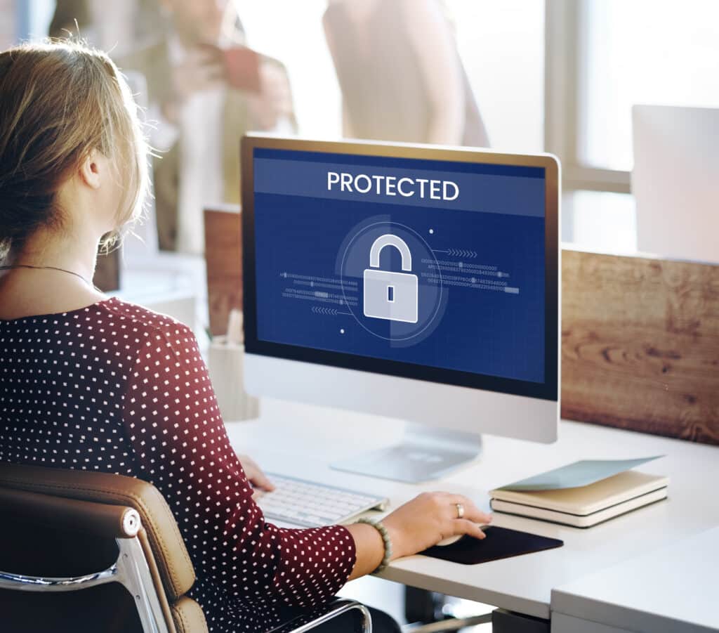 Woman working on a secure computer displaying a lock icon and the word “protected”